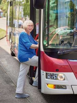 Eine Bewohnerin steigt vor dem Haus in den Bus