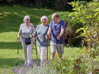 Drei Bewohnerinnen und Bewohner beim Spaziergang mit Stöcken