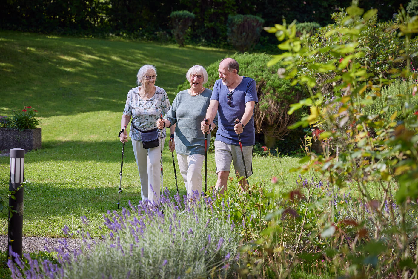 Drei Seniorinnen und Senioren beim Spaziergang im Garten